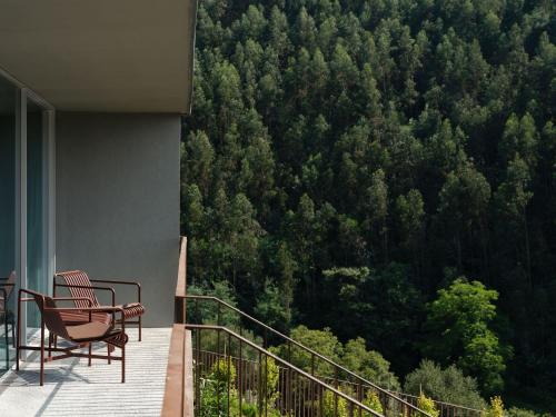 a balcony with chairs and a view of a forest at Octant Douro in Castelo de Paiva
