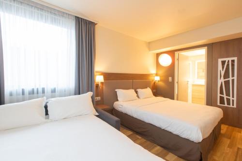 a hotel room with two beds and a window at Campanile Metz Centre - Gare in Metz