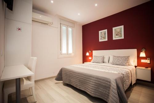 ein Schlafzimmer mit einem Bett und einer roten Wand in der Unterkunft Pensión Corbero in Madrid