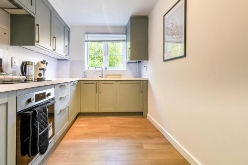 a kitchen with green cabinets and a wooden floor at Modern & comfy 4 bedrooms Corby house free parking in Great Oakley