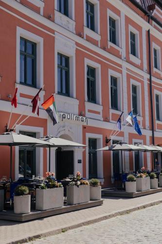 a building with tables and umbrellas in front of it at Pullman Riga Old Town in Rīga