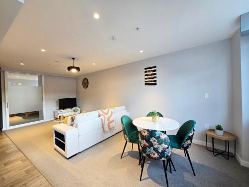 a living room with a white couch and a table and chairs at Central Lower Hutt 2BR Stay in Lower Hutt