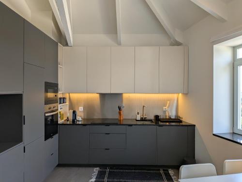 a kitchen with white cabinets and a black counter top at Castelo River View - NEW in Vila Nova de Gaia