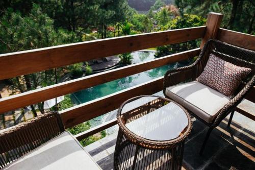 two chairs and a table on a balcony with a view of the water at AMAYA HOME - Lodge, Spa & Restaurant in Hanoi