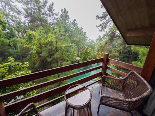 two chairs and a table on a porch with trees at AMAYA HOME - Lodge, Spa & Restaurant in Hanoi