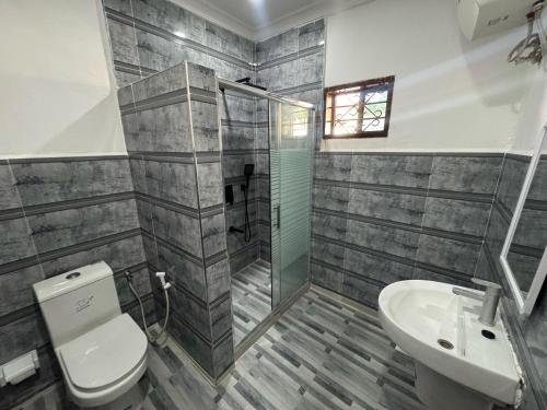 a bathroom with a shower and a toilet and a sink at Cozy Stay Near Zanzibar Airport in Zanzibar City