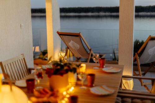 a table with chairs and a view of the water at Raža - Beachfront Apartment on Rab - Sea View & Private Boat Dock in Barbat na Rabu