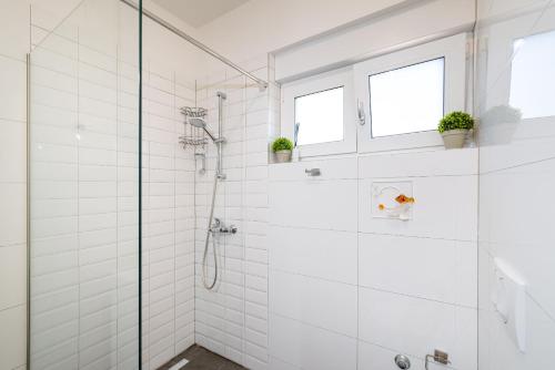 a bathroom with a shower with white tiles at Apartment Lipotica 1 in Nin