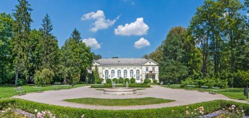 a large white building with a fountain in a park at Villa Polonia in Jelenia Góra
