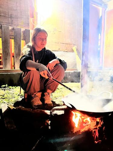 a woman is stirring a pot on a fire at PANORAMA BUNGALOWs in Tetebatu