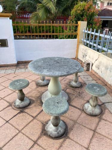 a stone table and four stools on a patio at Casa D' Bernam in TanjongMalim