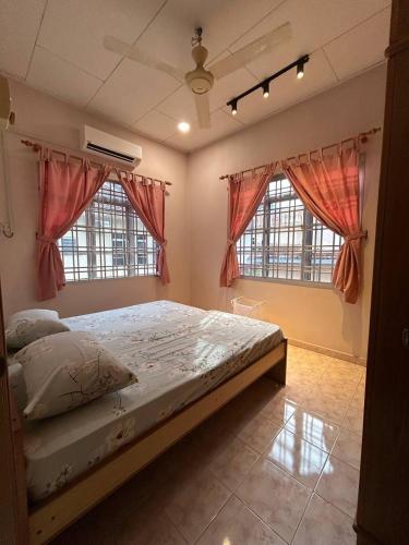 a bedroom with a bed and two windows at Casa D' Bernam in TanjongMalim