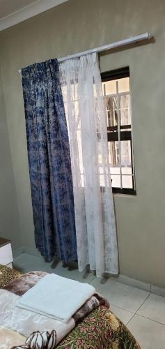 a bedroom with a bed and a window with curtains at Binu Motel in Kempton Park