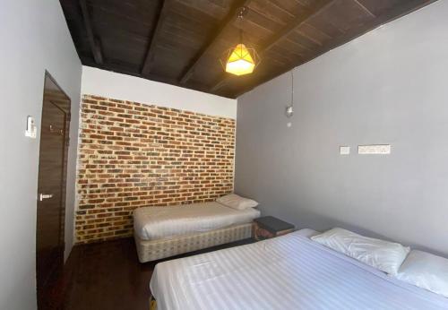 a room with two beds and a brick wall at Le Lodge Villa in Kuantan