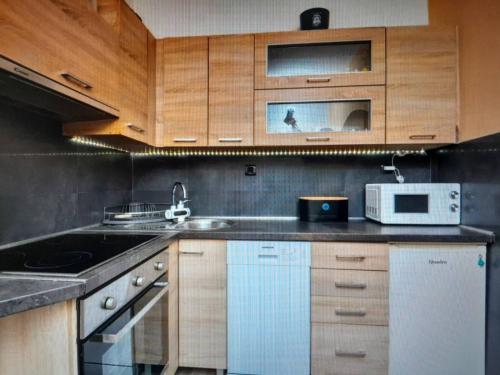 a kitchen with wooden cabinets and a sink and a microwave at Apartments Roza in Dramalj