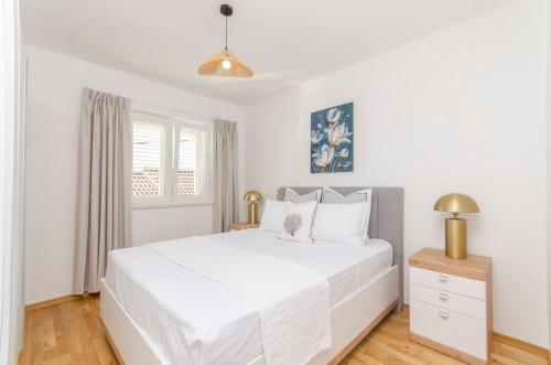 ein weißes Schlafzimmer mit einem weißen Bett und einem Fenster in der Unterkunft Apartments Quokka in Tribunj