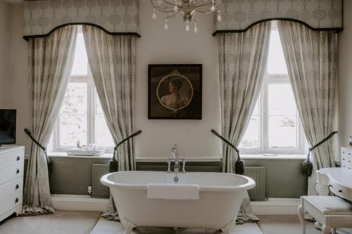 a bathroom with a tub and two windows at Allington Manor in Allington