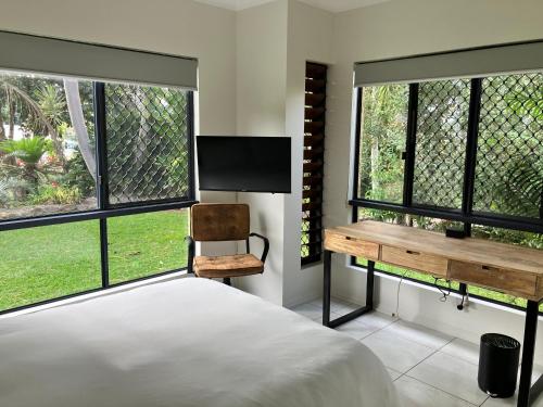 a bedroom with a bed and a desk and two windows at Relaxed Tropical Living in Caravonica