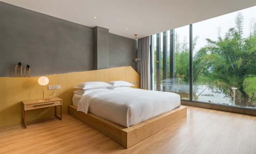 a bedroom with a large bed and a large window at Chen Jia Garden Hotel in Xingping