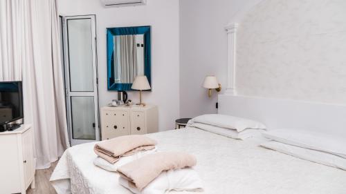 a white bedroom with two beds and a television at Bellavista Terme Resort & Spa in Montegrotto Terme