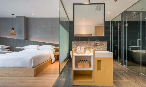 a bedroom with a bed and a bathroom with a shower at Chen Jia Garden Hotel in Xingping