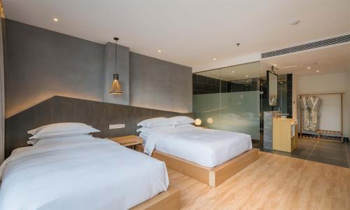 a bedroom with two beds and a walk in shower at Chen Jia Garden Hotel in Xingping