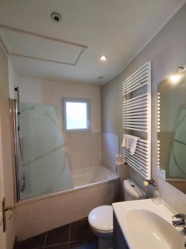 une salle de bain avec une baignoire, des toilettes et un lavabo dans l'établissement Le Haut-Val Résidences, à Bellême