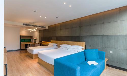 a bedroom with two beds and a blue couch at Chen Jia Garden Hotel in Xingping