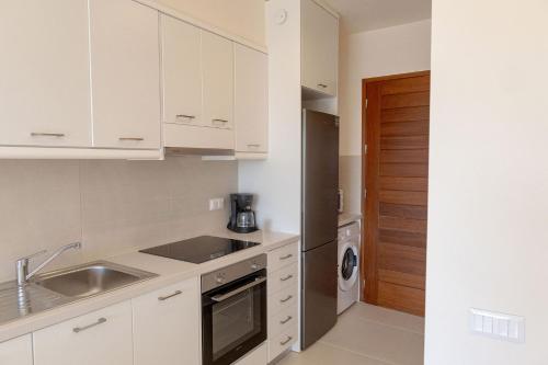 Una cocina blanca con fregadero y lavavajillas. en Phaedrus Living Seaside Thalassa Cretan 203, en Módhion