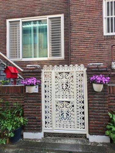 a white gate in front of a brick house with flowers at Sophie House foreigners women only in Seoul