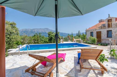 a patio with two chairs and an umbrella next to a swimming pool at House Nikica in Korčula