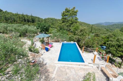 a blue swimming pool with chairs and an umbrella at House Nikica in Korčula