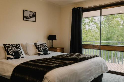 a bedroom with a bed and a large window at Rooke River Lodge in Jindabyne