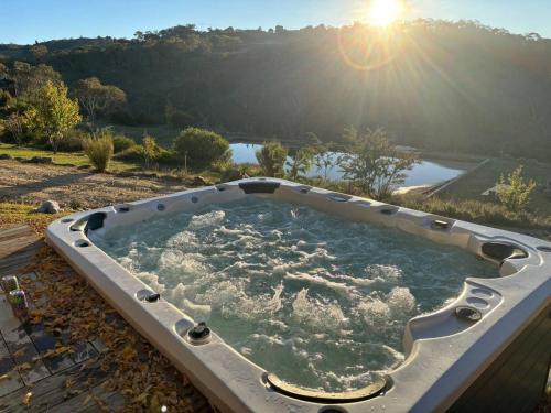 a jacuzzi tub with the sun in the background at Rooke River Lodge in Jindabyne
