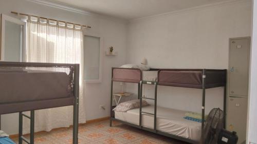 dwa łóżka piętrowe w pokoju z oknem w obiekcie Banana Surf House w mieście Los Cristianos