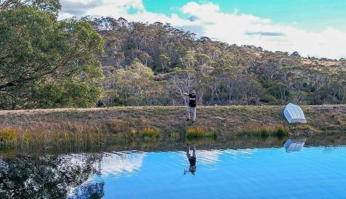 a person is standing on the shore of a lake at Rooke River Lodge in Jindabyne