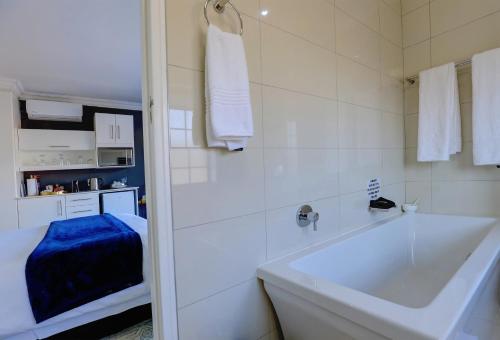 a white bathroom with a tub and a sink at African Oceans Manor on the Beach in Mossel Bay