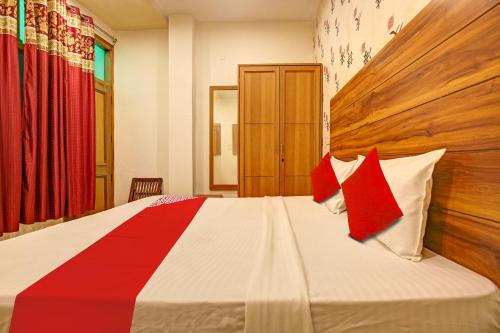 a bedroom with a large bed with red and white pillows at Hotel O NR Residency in Banūr