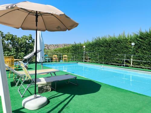 - Piscina con mesa, sombrilla y sillas en Rainbow Apartment, en Scordia
