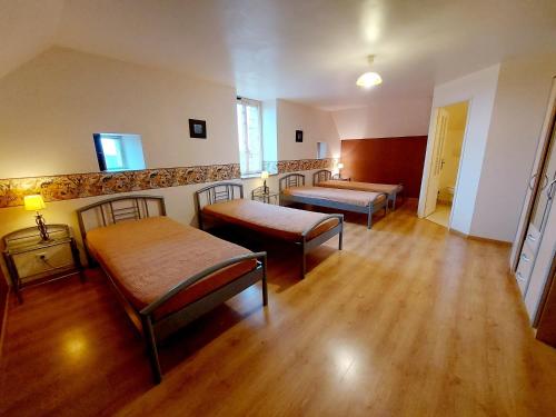a room with three beds and wooden floors at Les Preaux in Carelles