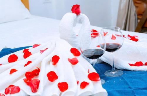 two glasses of wine and towels with hearts on a bed at BIG Apartment Ha Noi in Hanoi