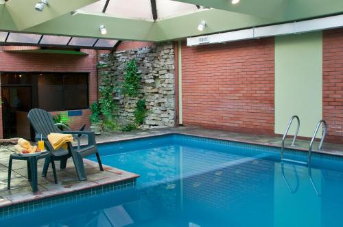 a swimming pool with a table and a chair next to it at Primacy Apart Hotel in Mar del Plata