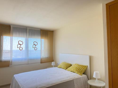 a bedroom with a bed with yellow pillows and a window at Dúplex con encanto en Castelldefels in Castelldefels