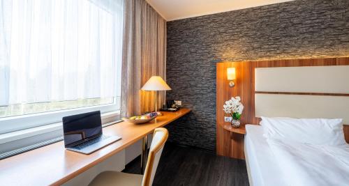 a hotel room with a desk with a laptop on it at Best Western Plaza Hotel Zwickau in Zwickau
