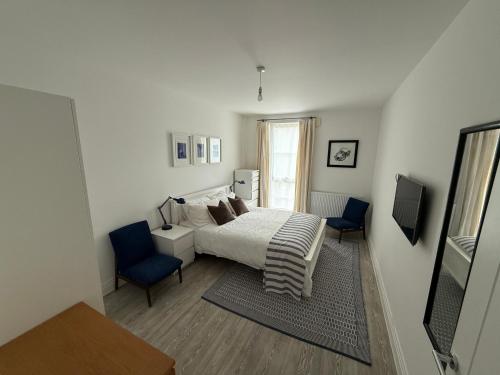 a bedroom with a bed and two blue chairs at Modern 2 Bed Apartment in North Oxford in Oxford