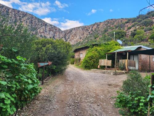 a dirt road with a building and mountains in the background at The Candle Cottage at Keurkloof Valley Family Farm in Uniondale