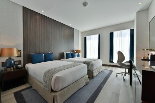 two beds in a hotel room with blue pillows at Bahrain Airport Hotel Airside Hotel for Transiting and Departing Passengers only in Muharraq