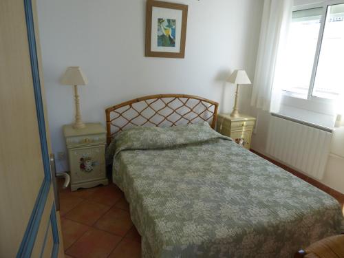 a bedroom with a bed and two lamps and a window at Appartement 1 chambre terrasse vue sur mer in Le Grau-du-Roi