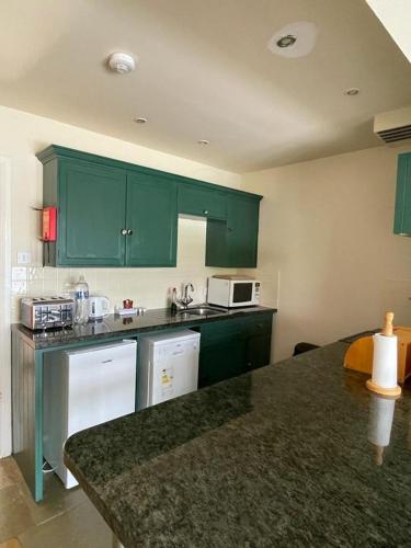 a kitchen with green cabinets and a counter top at Lochside Apartment in Moffat
