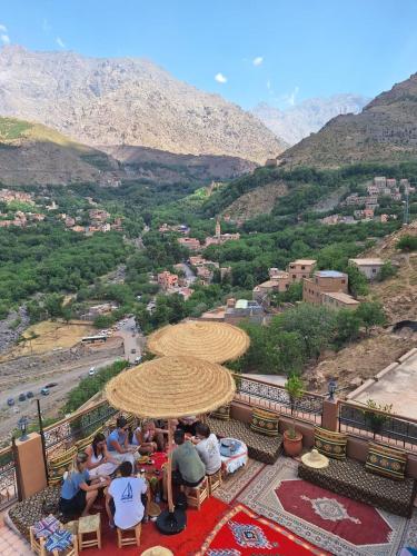 a group of people sitting at tables under an umbrella at Imlil Oasis - Oasis Dimlil in Imlil